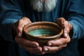 Old mans hands with an empty bowl on wood, representing the starkness of poverty