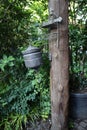 Old manual iron wash basin hanging on a log of wood in the garden