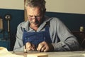 An old master with glasses works in a workshop Royalty Free Stock Photo