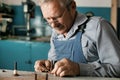 An old master with glasses works in a workshop Royalty Free Stock Photo