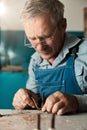 An old master with glasses works in a workshop Royalty Free Stock Photo