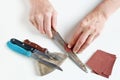 Old master tries to sharpen rusty kitchen knives on his white de