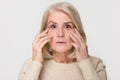 Old mature woman looking at camera worried about face wrinkles