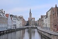 Old medieval houses and Poortersloge tower  along a canal in Bruges Royalty Free Stock Photo