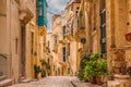 Old medieval street with yellow buildings, beautiful balconies and flower pots in Birgu, Valletta, Malta Royalty Free Stock Photo