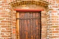 An old, medieval wooden door in a wall of bricks