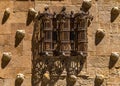 Old medieval wrought iron balcony divided into three cylindrical parts and shell moldings with their elongated shadows from the Royalty Free Stock Photo