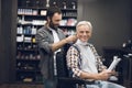 The old man is sitting in the barber`s chair in a man`s barbershop, where he came to cut his hair. Royalty Free Stock Photo