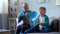 Old man holding Argentina flag, watching football with boy, worrying about game Royalty Free Stock Photo
