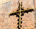 Old metal antique design christian cross attached on the red brick wall. Royalty Free Stock Photo