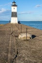 Old metal black and white lighthouse at end of cracked pier near Erie PA with people fishing and standing around  out at the end Royalty Free Stock Photo