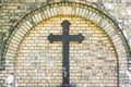 Old metal cross on brick wall background , rusty cross on grave