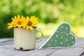 Old metal cup with flowers and a love symbol on a wooden table Royalty Free Stock Photo