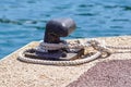 Old metal dock mooring pole with ring and rope for securing fishing boats Royalty Free Stock Photo