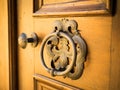 Old metal door handle knocker on a rough wooden background. Royalty Free Stock Photo