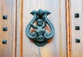 Old metal door knocker with a baby figurine on a wooden door