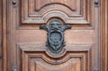 Old metal door knocker with decorations and a lion's head on a rustic wooden door. Royalty Free Stock Photo