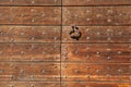 Old metal doorknocker on the wooden gate fixed with rivets