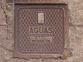 Old metal drain cover in Povoa de Varzim, Portugal with AGUAS lettering and crosshatch pattern