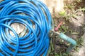 Old metal faucet and blue rubber tube that goes from metal pipe on the ground Royalty Free Stock Photo