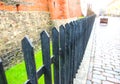 Old metal fence near the building. Medieval town with pebbles road