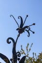 Old metal forged flower on a background of blue sky