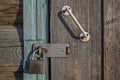 An old metal lock with traces of rust on the wooden door with a white-painted, battered handle bolted on screws, locked Royalty Free Stock Photo