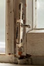 Old metal lock on a white wooden window frame. Old wooden window frame with a small rusty lock. Royalty Free Stock Photo