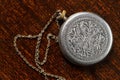 An old metal medallion with a chain and ornament on the surface.