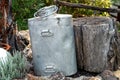 An old metal milk can, next to a large wooden log Royalty Free Stock Photo