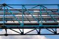 Old metal overhead pedestrian footbridge against blue sky