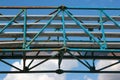 Old metal overhead pedestrian footbridge against blue sky