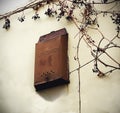 Old metal post box with russian writing for mail hanging on white plaster dirty wall