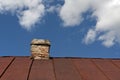 Old metal roof with brick chimney against cloudy sky. Royalty Free Stock Photo