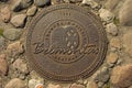 Old metal rusty sewer manhole cover on sand rock path