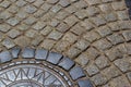 Old metal sewer hatch in the middle of the road, laid out of a smooth paving stone Royalty Free Stock Photo