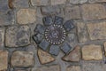 Old metal sewer hatch in the middle of the road, laid out of a smooth paving stone Royalty Free Stock Photo