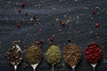 Old metal spoons with different kind of seeds and spices on black background Royalty Free Stock Photo