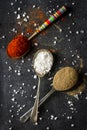 Old metal spoons with different kind of spices on black background Royalty Free Stock Photo