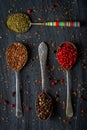 Old metal spoons with different kind of spices on black background Royalty Free Stock Photo