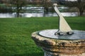 An old sundial set on a stone plinth or pedestal on a grassy lawn with a lake in the background Royalty Free Stock Photo