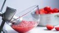 Old metal vintage manual meat grinder, plate with chopped tomatoes,pot with tomatoes on a white table. Making homemade adjika,