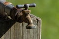 old metal water tap bolted onto a wooden post