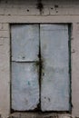 Old metal and wood door painted with white-blue paint against the background of an old white tiles Royalty Free Stock Photo