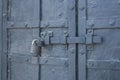 The old metal wrought-iron door is locked with a padlock. Closed metal lock.