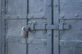 The old metal wrought-iron door is locked with a padlock. Closed metal lock. Royalty Free Stock Photo