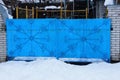 Old metallic blue gate with wrought pattern in the street in white snow Royalty Free Stock Photo