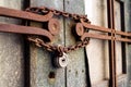 Old metallic padlock with rusty vintage chain hangs on old door
