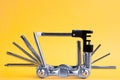 Old metallic unfold bike multi tool set with chain remover on a yellow background. Bicycle multifunction tool. Royalty Free Stock Photo