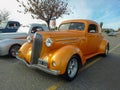 Old metallic yellow 1936 Chevrolet Master coupe street rod in a parking lot at a classic car show. Royalty Free Stock Photo